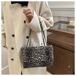 Close-up of leopard print shoulder bag with gold chain strap on a white coat
