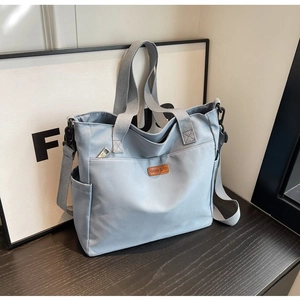 Detail view of light blue canvas tote bag with adjustable strap and side pockets