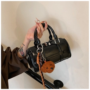 Close-up of black glossy PU leather boston bag with brown plush puppy charm