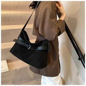 Photo lifestyle d'un grand sac cabas hobo en daim noir porté par un mannequin en extérieur