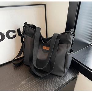 Detailed view of black canvas tote bag with adjustable shoulder strap and side pockets