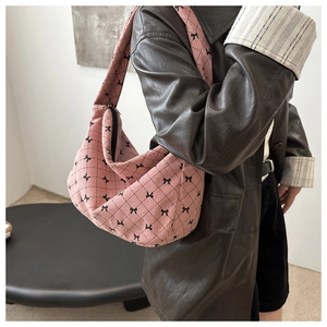 Dettaglio borsa hobo in velluto a coste rosa con motivo a rombi e fiocchi indossata a spalla