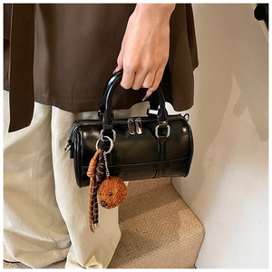 Detail of black glossy PU leather Boston bag with plush dog charm and silver zippers
