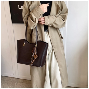 Détail du sac cabas marron foncé en similicuir avec charme noué sur un mannequin
