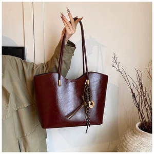 Détail du cabas en cuir PU bordeaux avec anneau métallique et pompon vintage