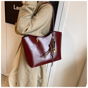 Détail d'un sac cabas en cuir ciré rouge foncé avec garnitures dorées et pendentif