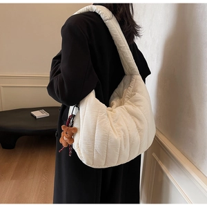 Detail view of white quilted puffer shoulder bag with a cute brown plush bear charm