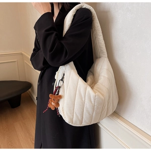 Detail view of off-white quilted shoulder bag with cute brown plush bear charm