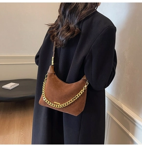 Detailed close-up of brown suede hobo bag with a decorative gold chain and leather strap