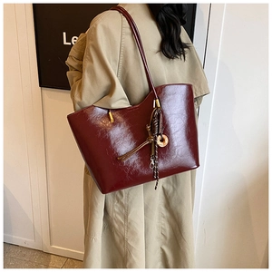 Vue détaillée du sac cabas en similicuir bordeaux brillant avec un charm artistique chic