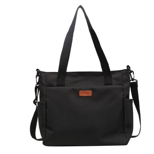 Minimalist black canvas tote bag with adjustable strap and side pockets for commuting