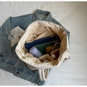 Detailed interior of beige canvas tote bag showing large capacity and multi-pocket layout