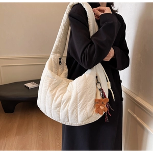 Close-up of white quilted cloud shoulder bag with a cute brown plush bear pendant charm