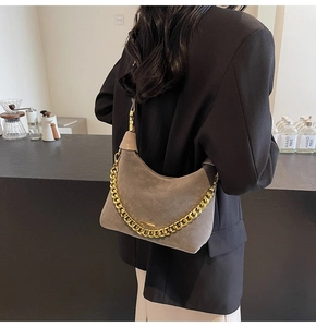 Detail of grey suede hobo bag featuring a chunky gold chain and slim shoulder strap
