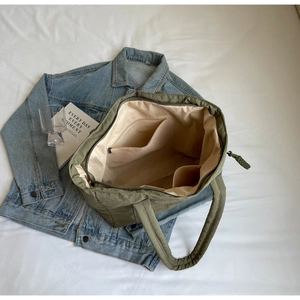 Detailed internal view showing zippered pocket and open compartments in army green tote bag