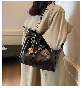Detail of coffee brown tote bag featuring baseball charm and metallic chain strap