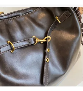 Close-up of glossy brown PU leather texture and vintage golden metal buckle details