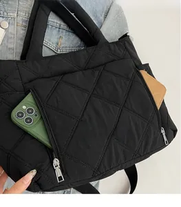 Close-up of black quilted tote bag showing functional external zipper pockets and storage