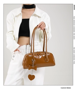 Close-up of brown oil-wax leather shoulder bag with metallic heart and bow charms
