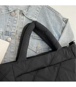 Close-up of the black quilted tote bag with soft diamond stitching on denim jacket