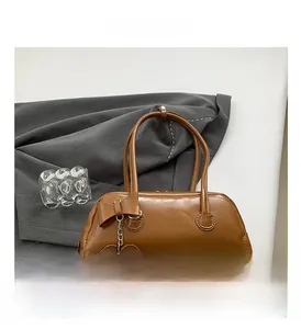 Detail of a brown PU leather handbag featuring a stylish bow and heart metal pendant charm