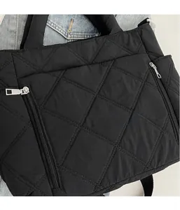 Detailed close-up of a black quilted puffer handbag featuring dual zipper pockets