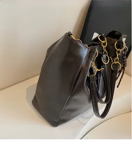 Detail of soft brown PU leather tote bag featuring a bold chunky gold chain handle