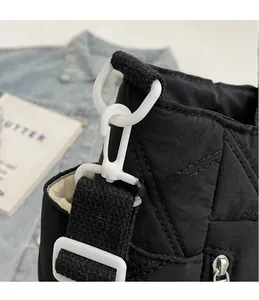 Detail shot of the removable white hook on a black quilted tote bag with diamond stitching