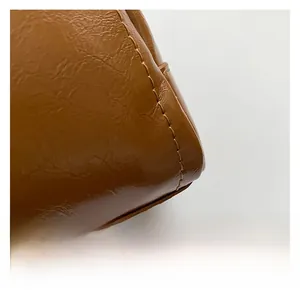 Close-up of brown oil wax leather texture and precise stitching on the shoulder bag