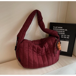 Chic burgundy quilted puffer tote bag with plush bear charm and woven tassel details