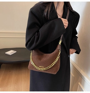 Detail of dark brown suede half-moon bag with decorative thick gold chain and leather strap