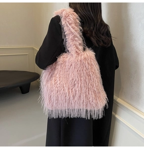 Close-up of pink fluffy faux fur handbag worn on the shoulder with a black coat