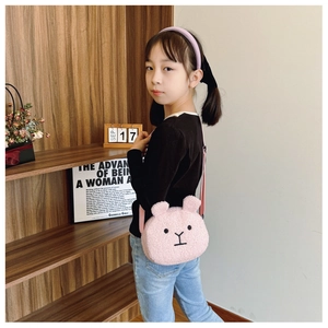 Close-up of pink plush bunny crossbody bag and purple bow headband worn by a girl