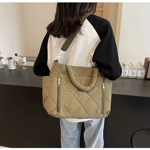 Detail of olive green quilted tote bag with diamond stitching and side silver zipper pocket