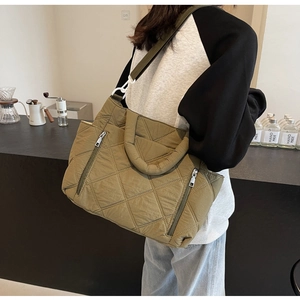 Detail of olive green quilted puffer tote bag with rhombus texture and wide strap