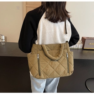 Detailed close-up of olive green quilted crossbody bag with dual vertical zipper pockets