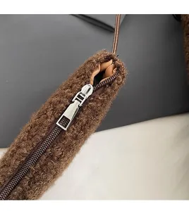 Close-up of a smooth silver metal zipper on a dark brown fuzzy plush shoulder bag