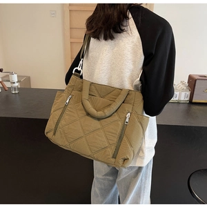 Detail of olive green quilted tote bag with vertical zippers and detachable strap