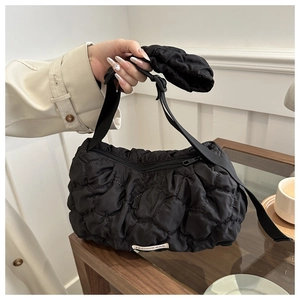 Close-up of black quilted puffer shoulder bag featuring unique bubble texture and woven label