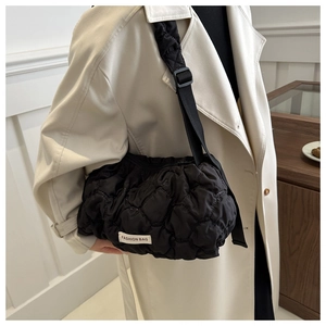 Detail of black quilted puffer tote bag featuring fashion tag and adjustable strap