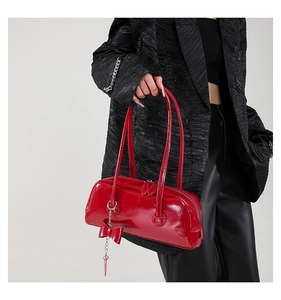 Detail of red glossy patent leather bowling bag with bow pendant and dual zippers