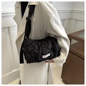 Detail of black quilted puffer tote bag featuring white fashion label and soft texture