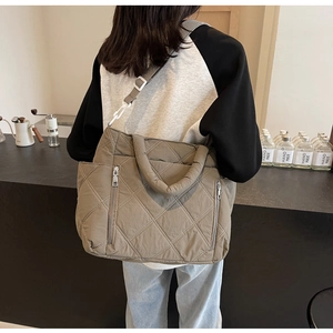 Detail of quilted brown tote bag showing the textured rhombus stitching and zipper pocket