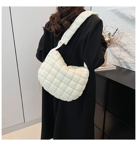 Detail of white quilted puffer bag featuring soft padded texture and adjustable shoulder strap