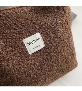 Detailed macro view of brown faux fur texture and woven label on a vertical crossbody bag