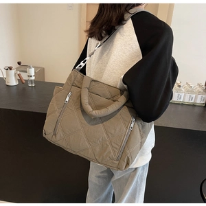 Detail of khaki green quilted tote bag featuring diamond patterns and side zipper pocket