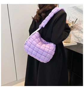 Detail of light purple quilted puffer bag with wide adjustable strap on a shoulder