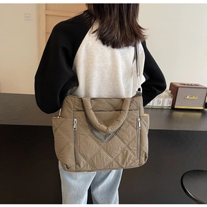 Detailed view of brown quilted shoulder bag with vertical zippers and diamond texture