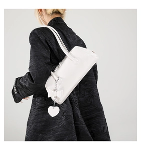 Close-up of white PU leather shoulder bag with decorative bow and heart pendant detail