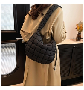 Detail of black quilted cloud bag showing lightweight nylon texture and padded shoulder strap